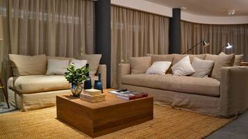 Una sala de estar moderna con dos sofás color beige, una mesa de centro de madera y un ventanal con cortinas.