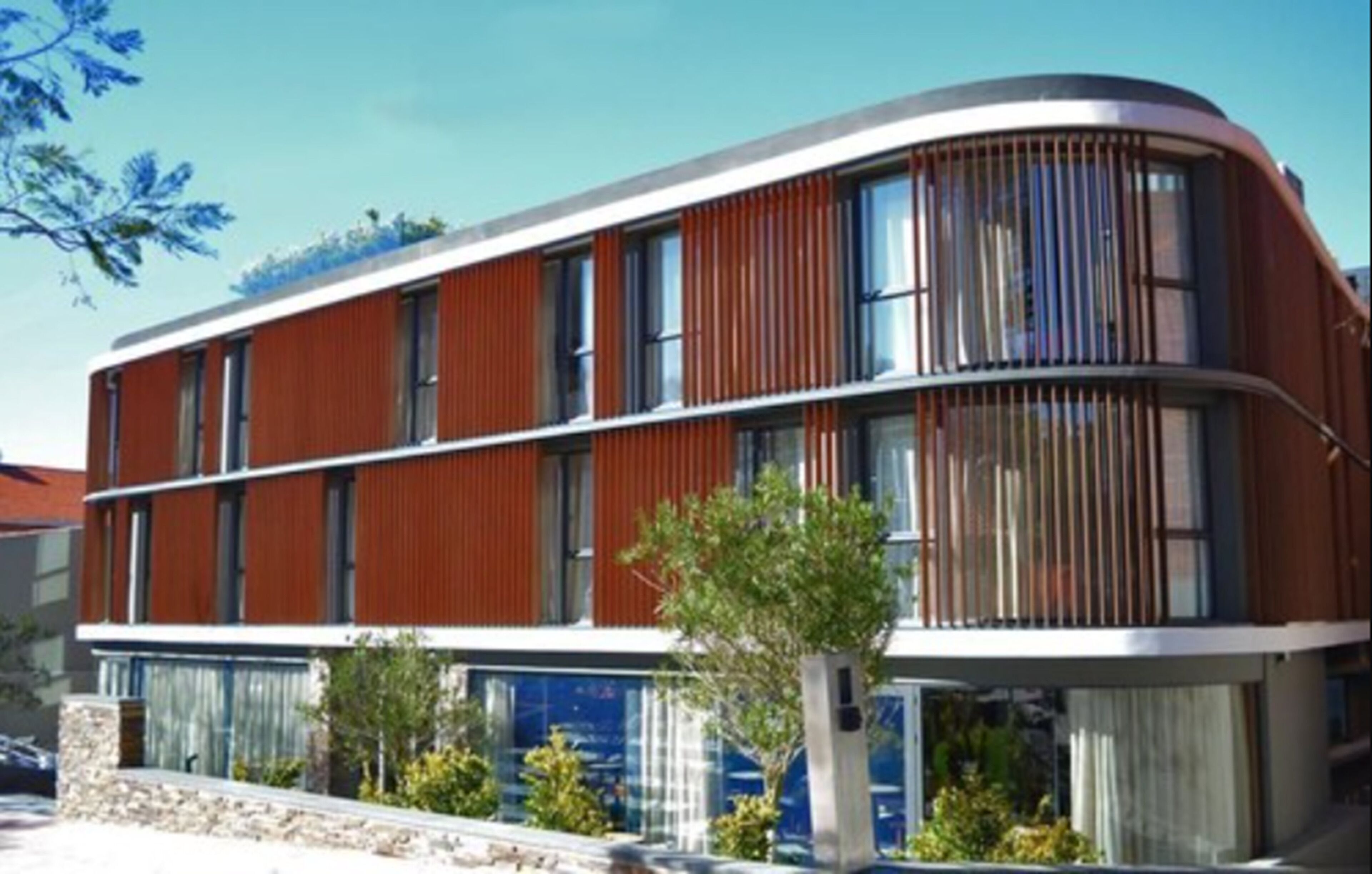 Un edificio moderno con fachada curva, ventanas amplias y base de piedra.