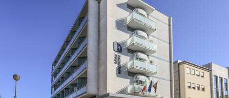 A modern hotel with multiple balconies, a prominent 'Hotel' sign, and flags.