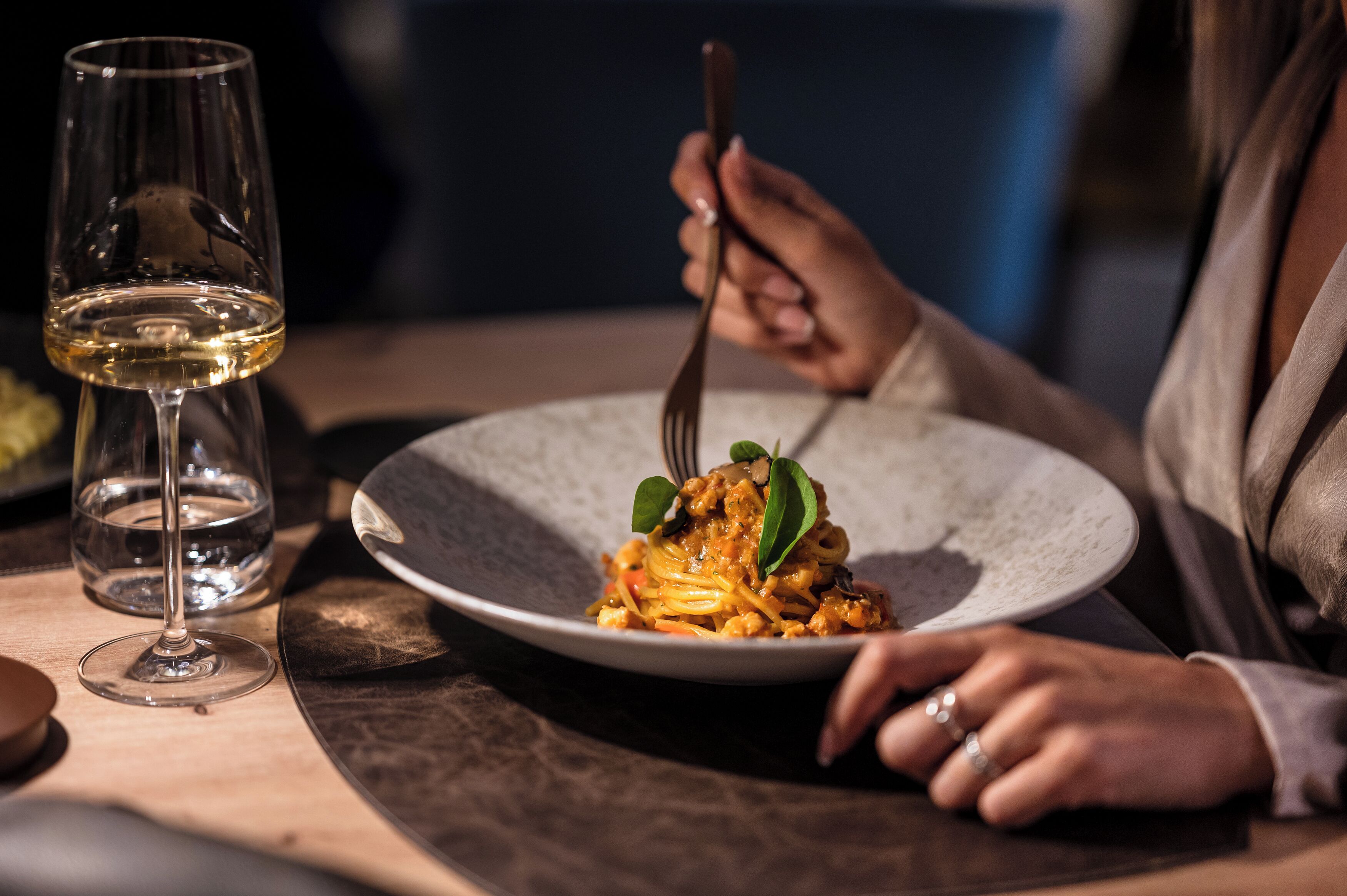 Et spisebord med en tallerken pasta, et vinglas og en gaffel.