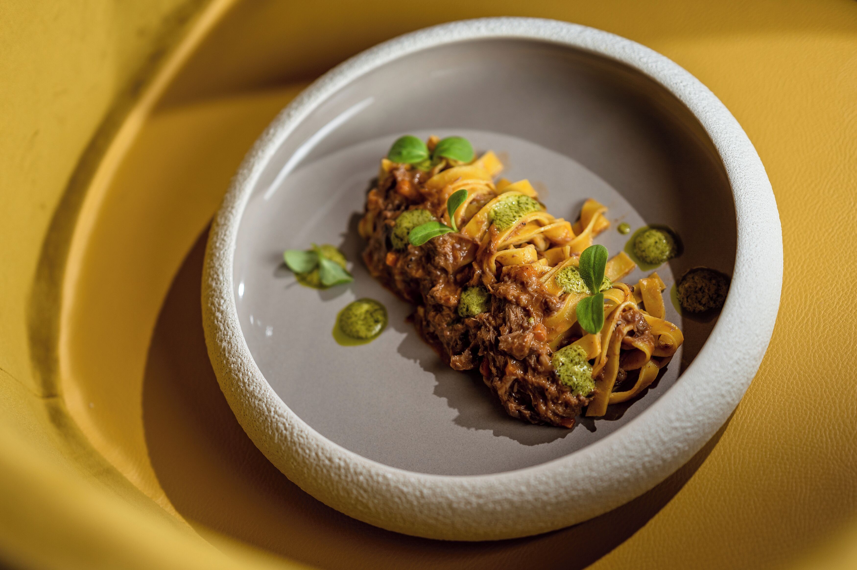 Une assiette de nourriture, accompagnée d’un bol à la texture particulière, le tout sur un fond jaune.