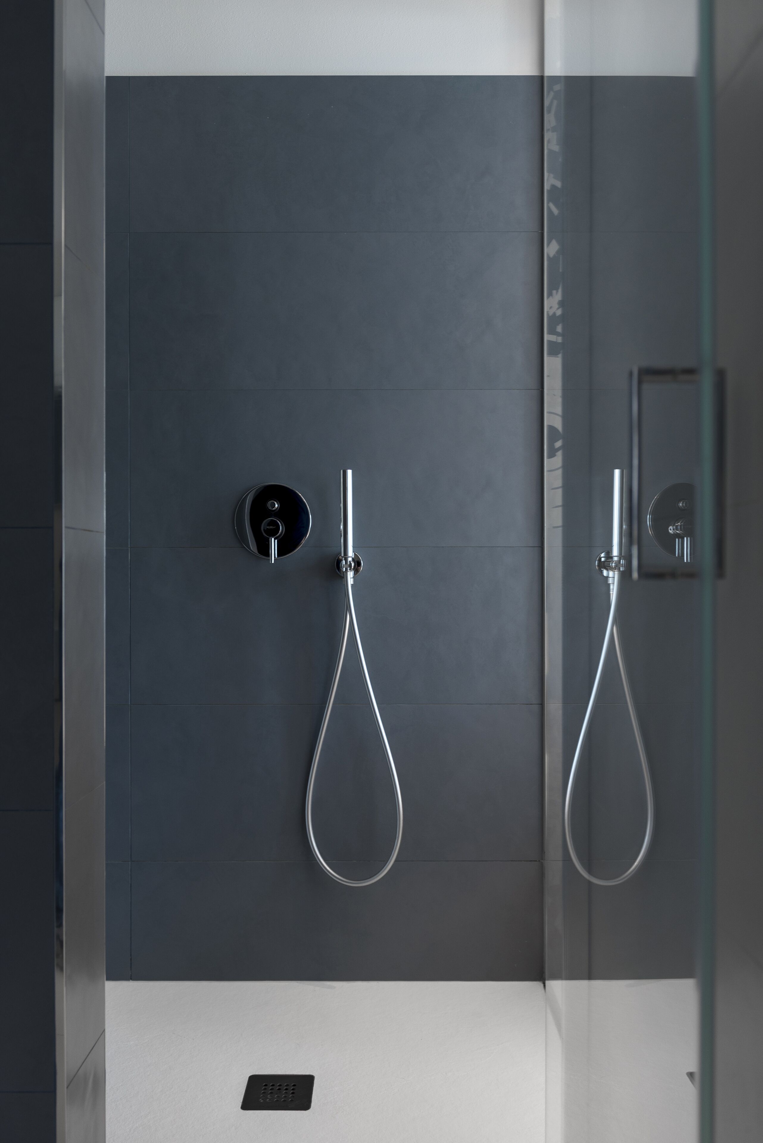 A modern shower enclosure with a glass door and a control panel on the wall.