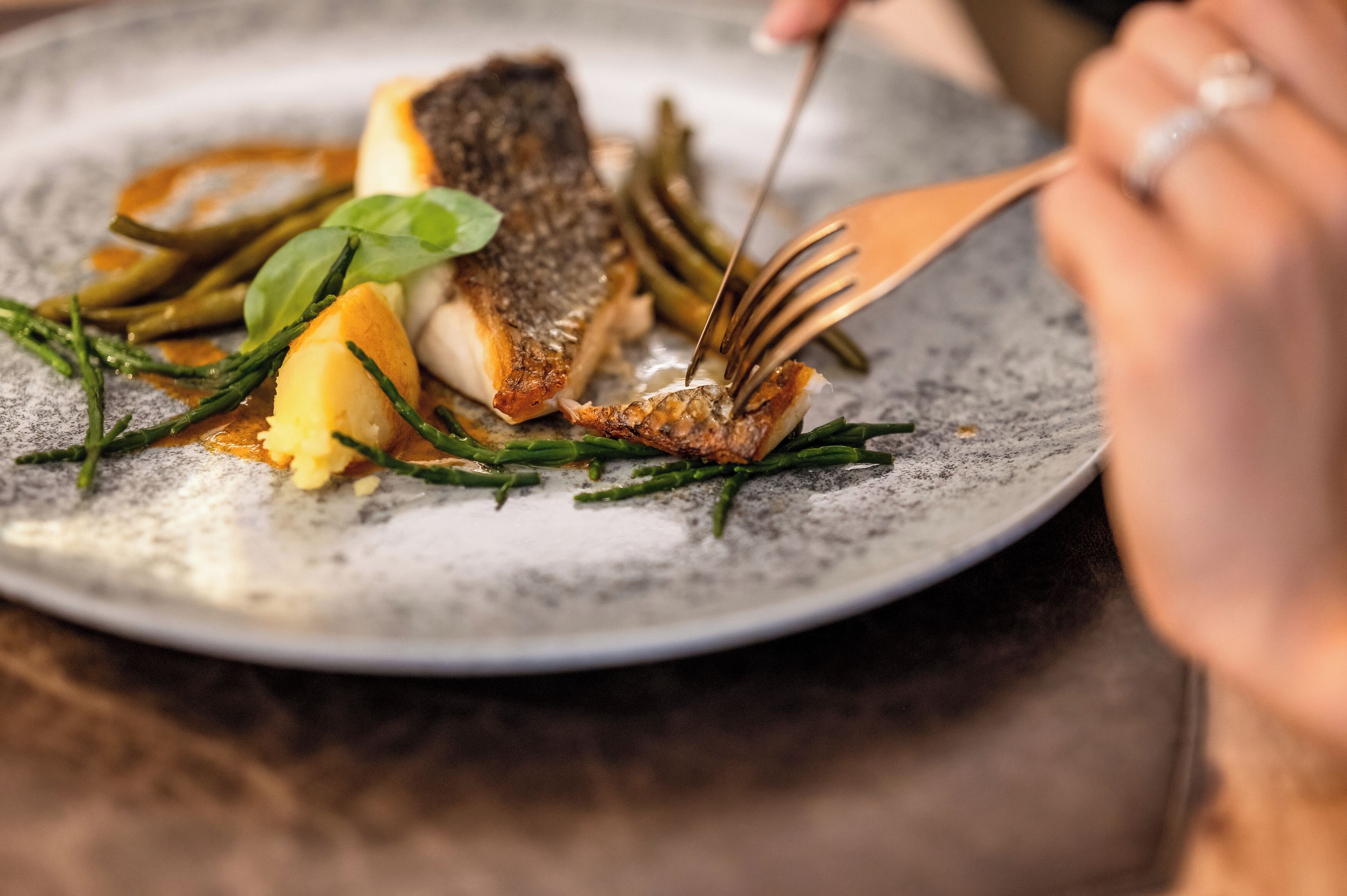 A plate of food with a fish, vegetables, and a fork.
