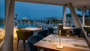 Un restaurante con mesas dispuestas para comer, con vista a una piscina y al mar.