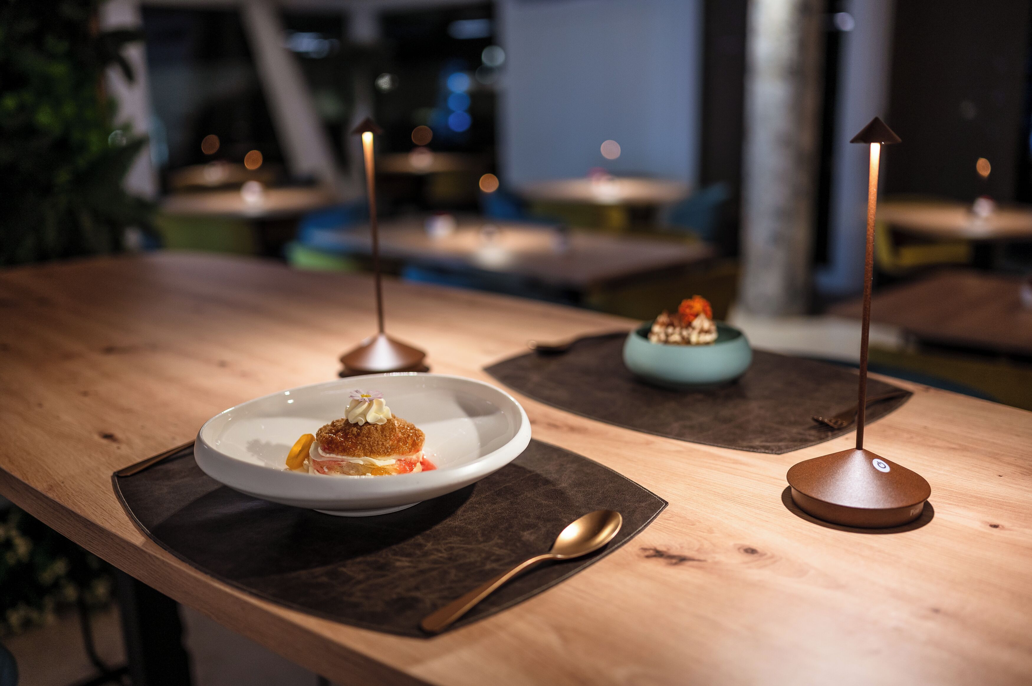 A restaurant setting with a wooden table, a dessert plate, and a candle holder.
