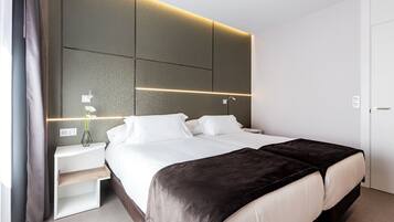 A modern hotel room with a large bed, bedside tables, and a wall-mounted light fixture.
