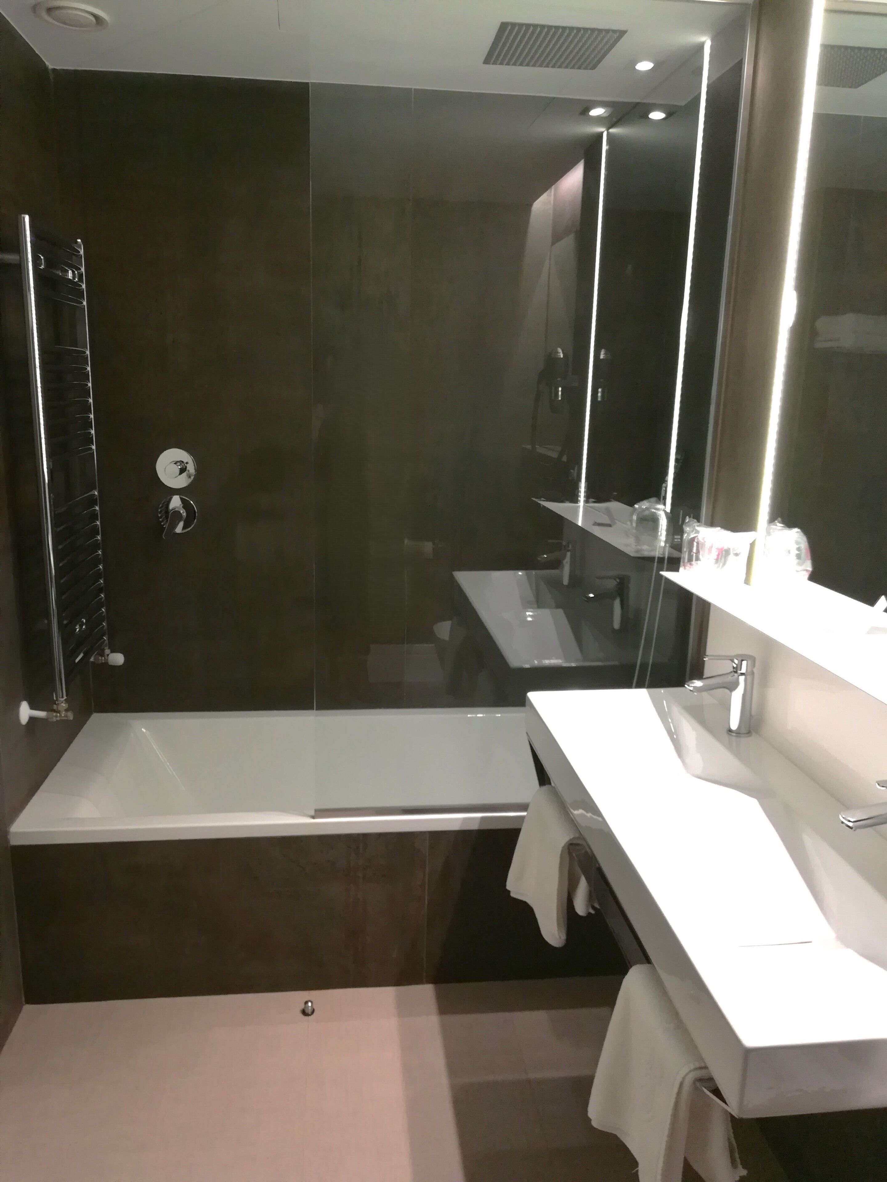 Un baño moderno con bañera, lavamanos y un espejo grande.