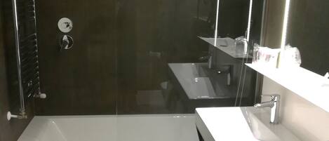 A modern bathroom with a bathtub, a sink, and a large mirror.
