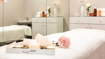 A hotel room with a bed, a vanity with toiletries, a mirror, and a small table with candles and flowers.