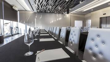 Un salón de conferencias con una larga mesa, sillas y una pantalla para proyector.
