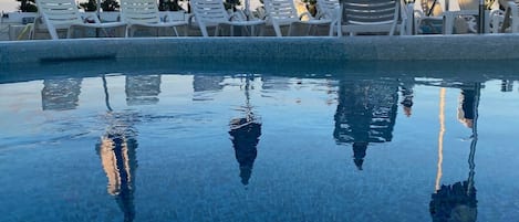 Una piscina al aire libre de temporada, sombrillas, tumbonas