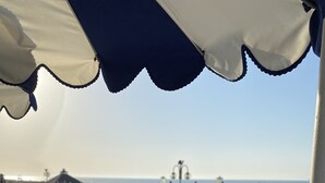 Et poolområde med parasoller, liggestole og havudsigt.