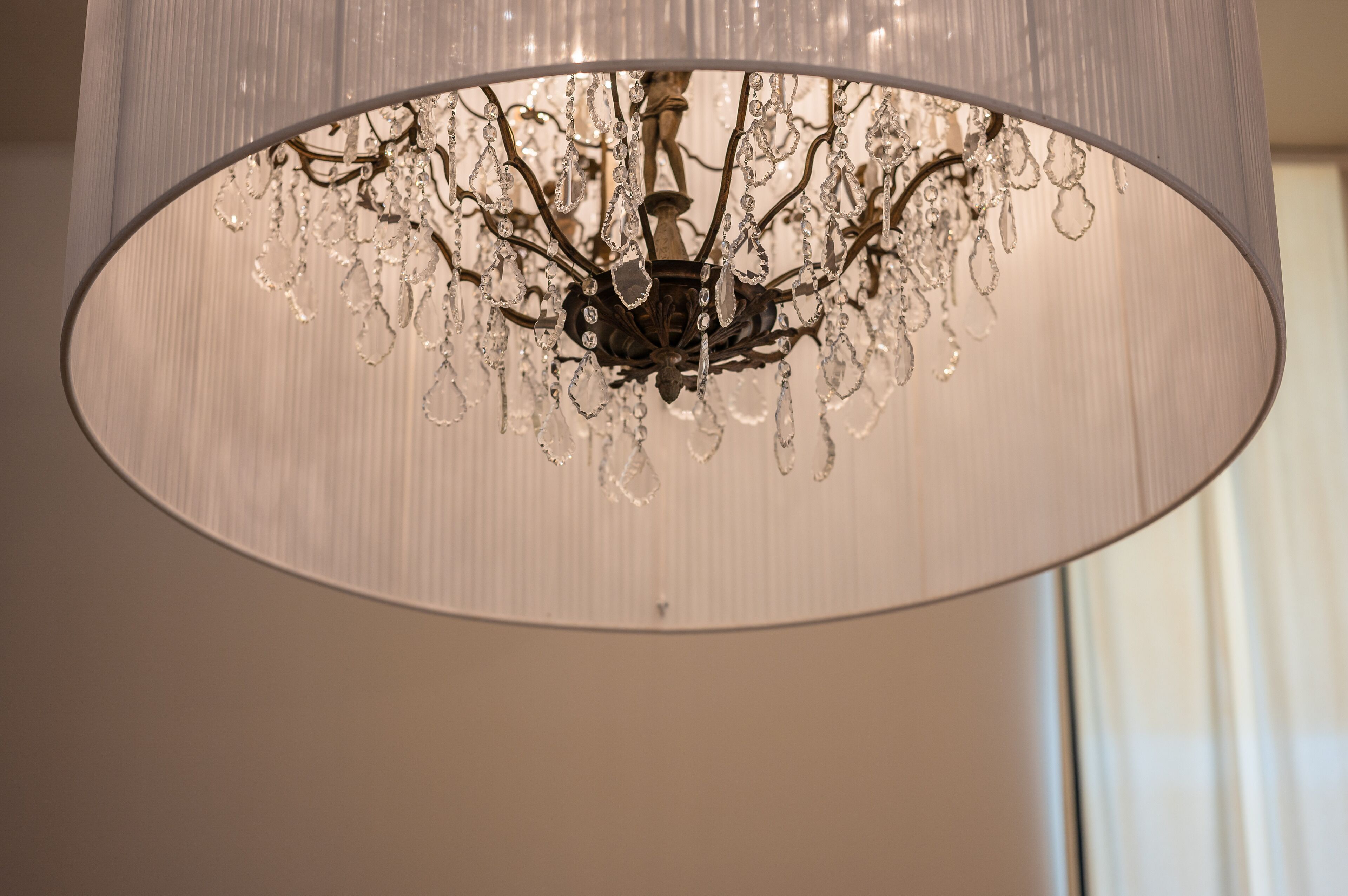 A chandelier with crystal decorations hanging from a cylindrical shade.
