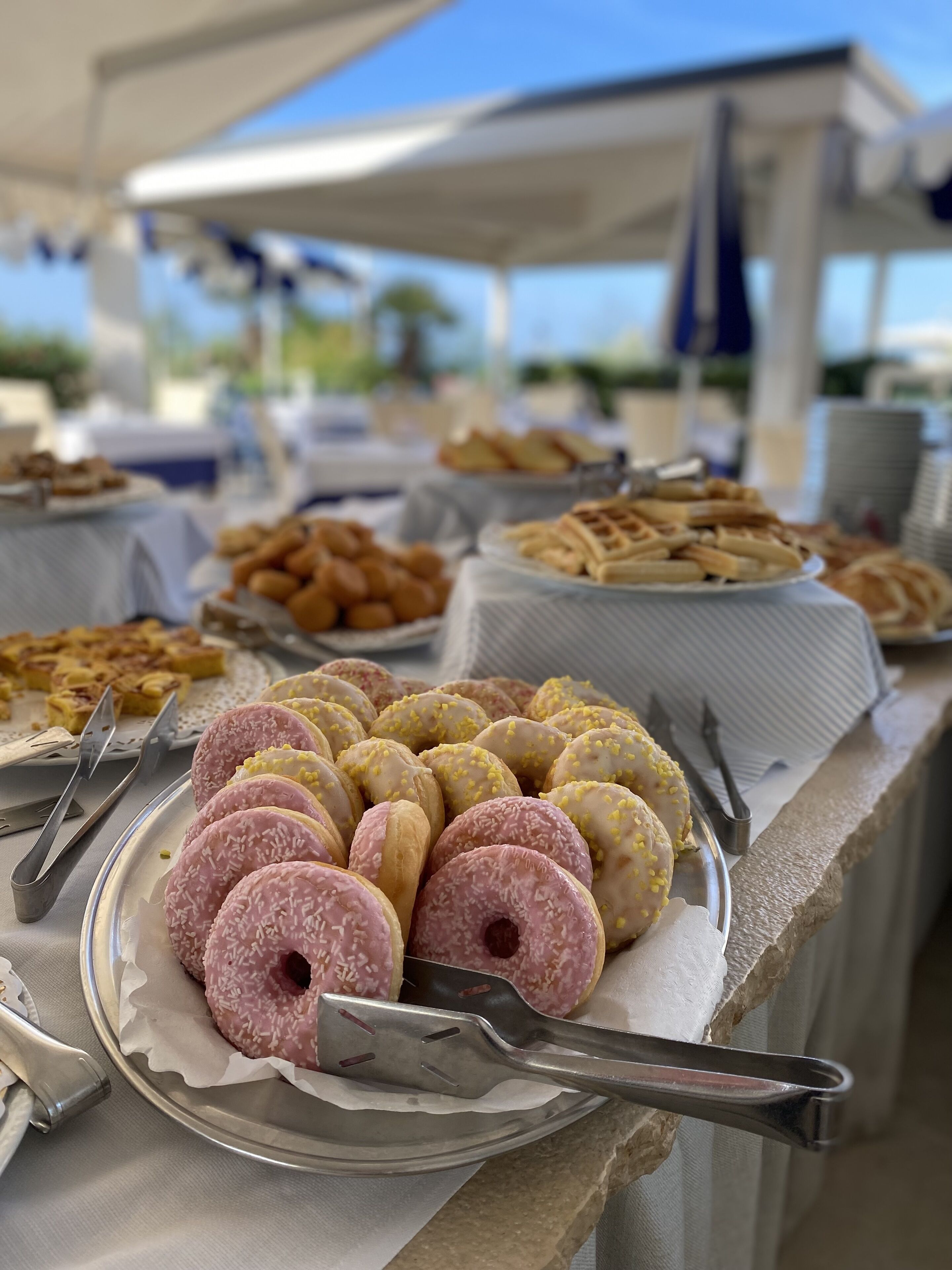 Une table de buffet avec divers pâtisseries et une assiette de beignets.