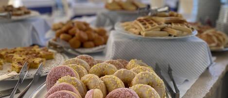 Una mesa de buffet con diversas pastelerías y un plato de rosquillas.