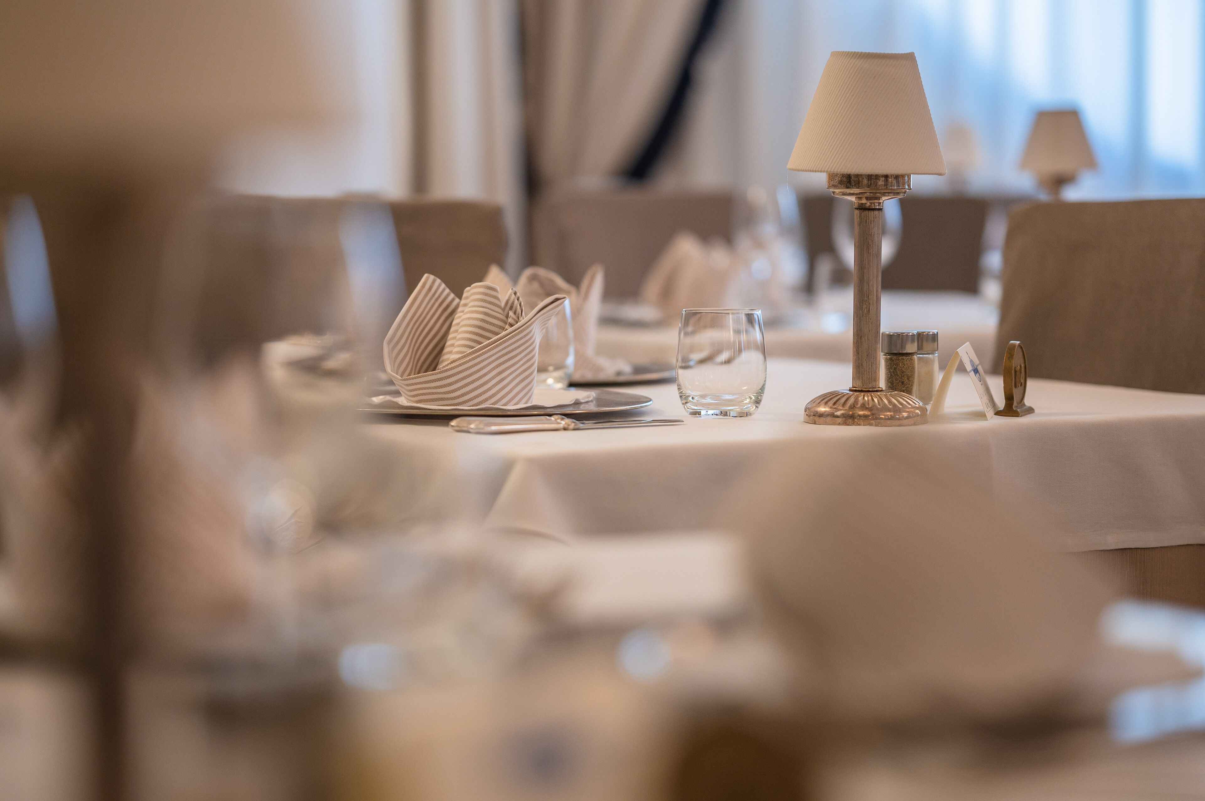 Une table à manger dressée avec une lampe, de la verrerie et des serviettes pliées.
