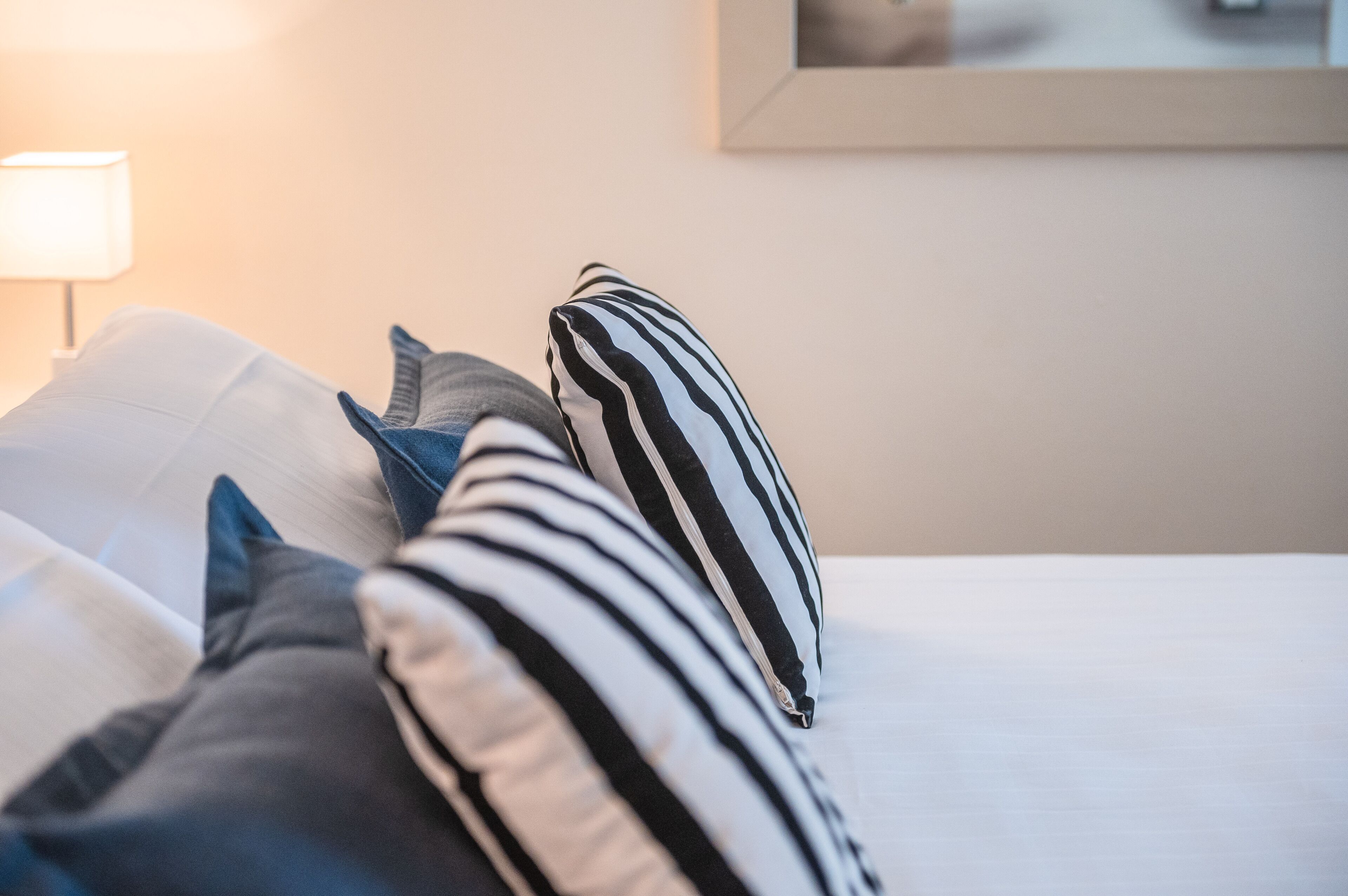 Una cama con almohadas a rayas y una colcha blanca.