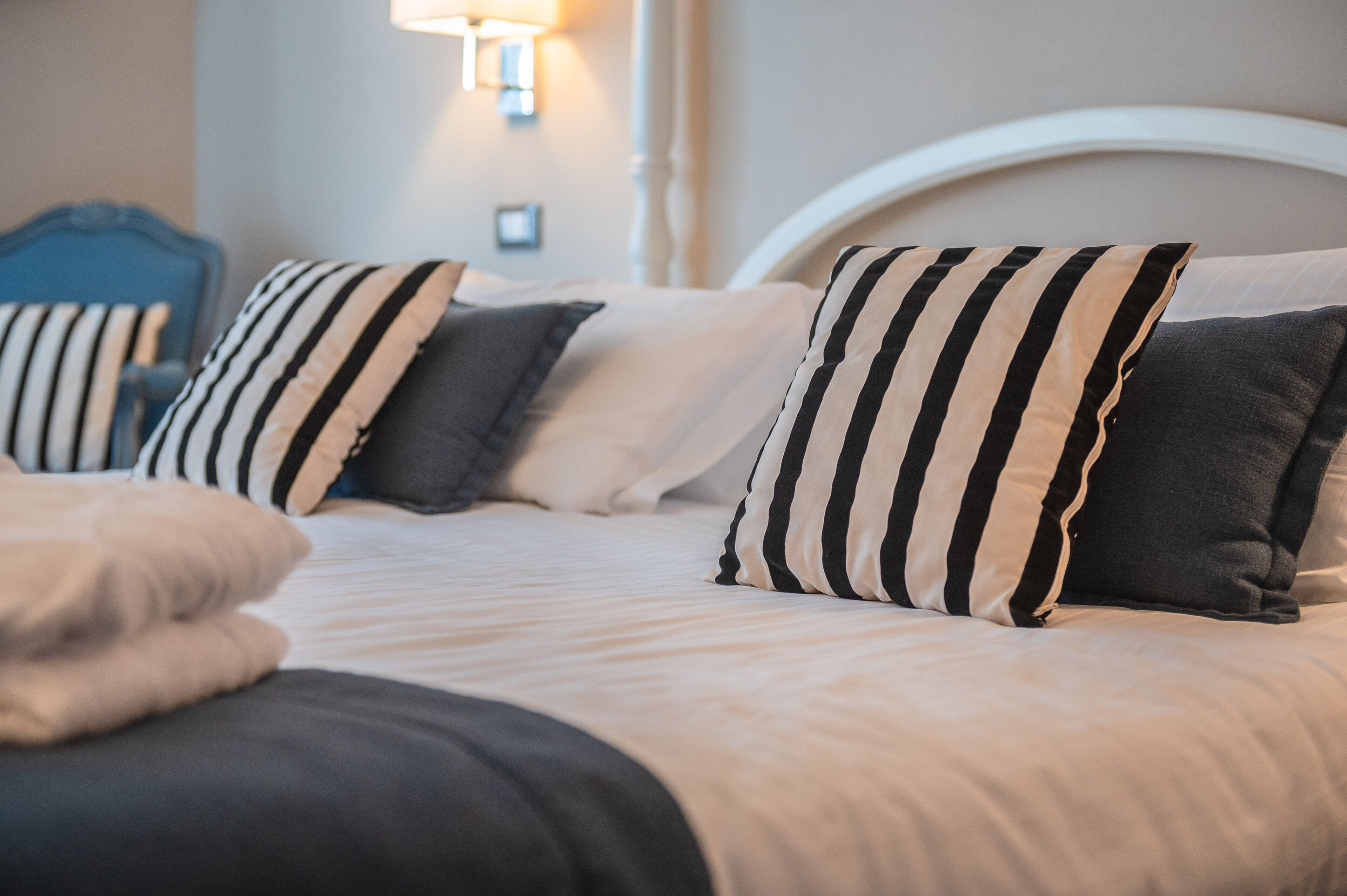 A neatly made bed with striped pillows and a white headboard.