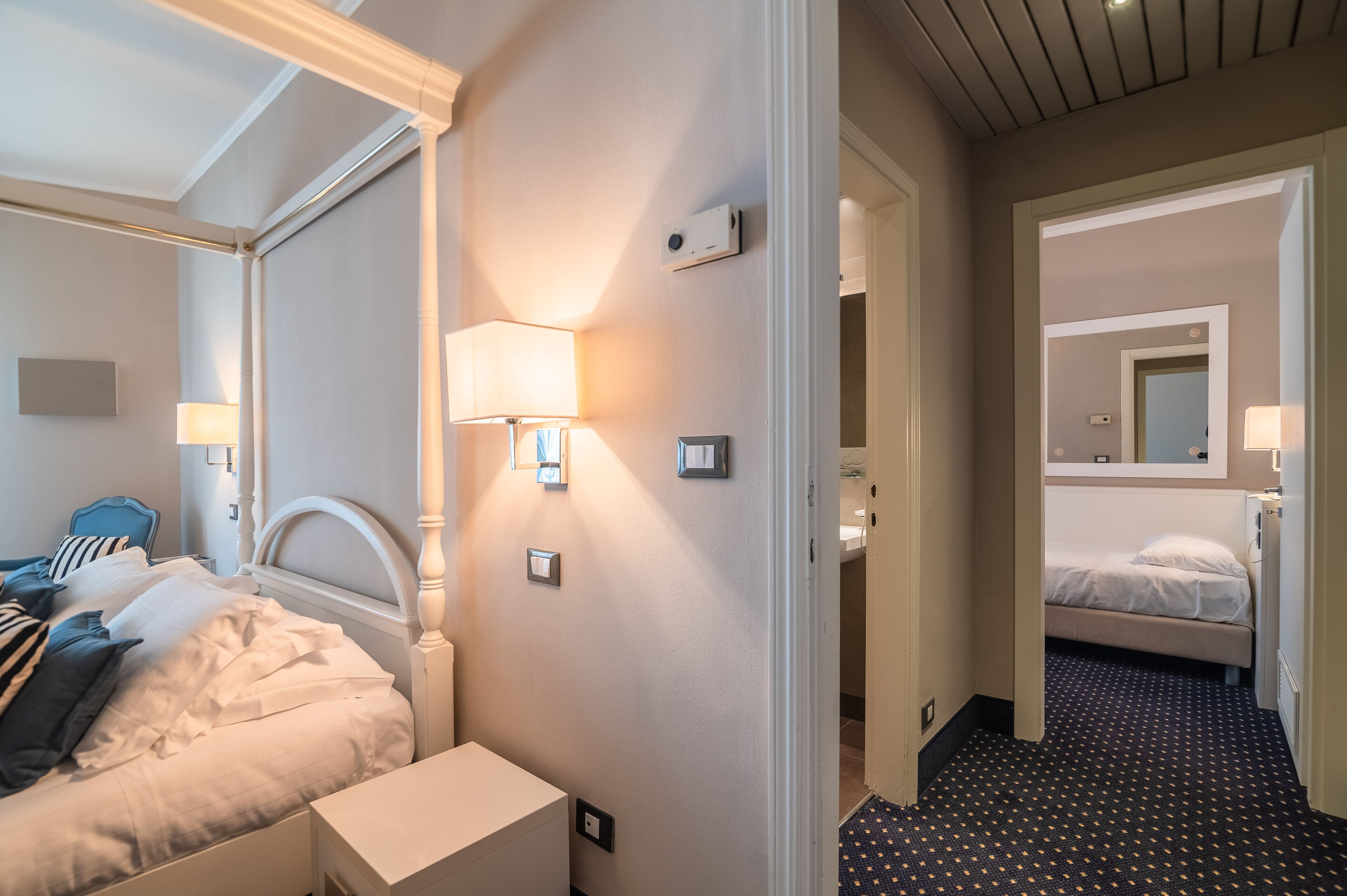Een hotelkamer met een bed, nachtkastje, lamp en een spiegel.