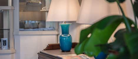 A well-lit room with a blue vase lamp, a white lamp, and a display cabinet with handbags.