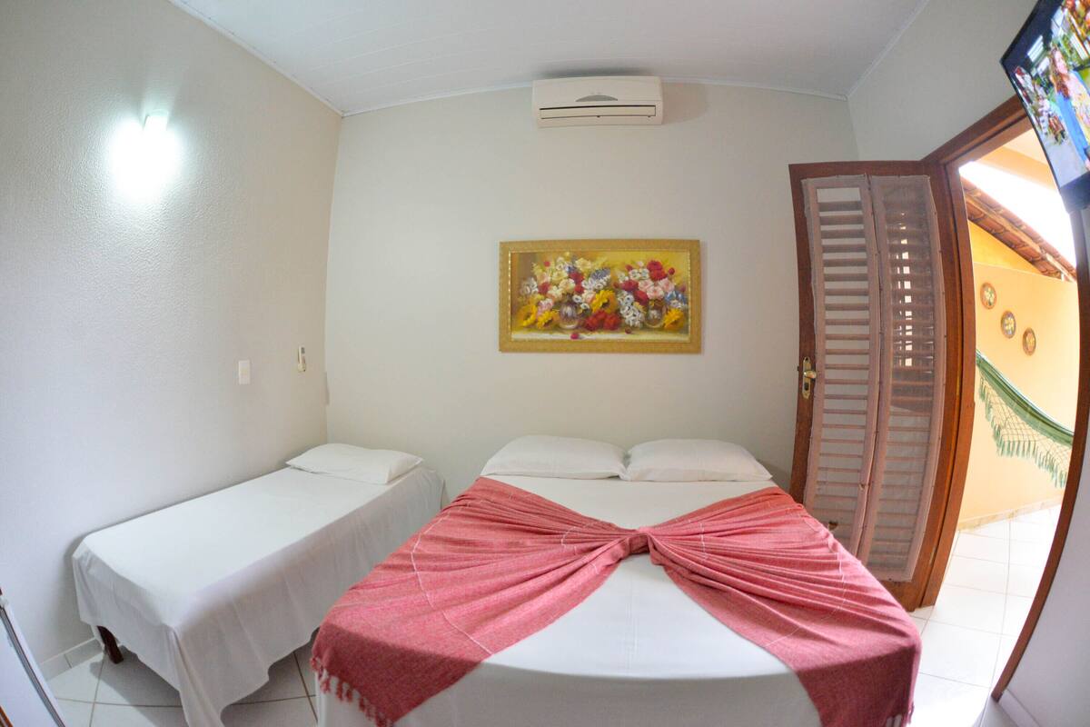 A room with two beds, one with a pink blanket and a painting on the wall.