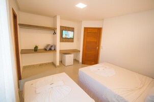 Et hotelværelse med to senge, et fjernsyn, et lille skrivebord og en trædør.