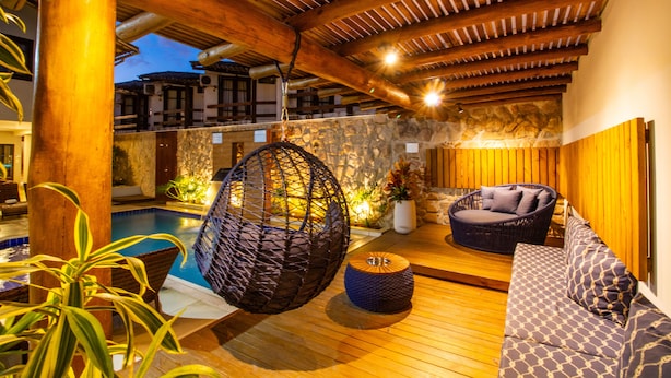 A wooden deck with a pool, a hanging chair, and a sofa. - Hotel Bem Brasil (Porto Seguro)