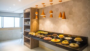 A modern kitchen with a long counter displaying various dishes, pendant lights, and a hexagonal patterned wall. - Hotel Bem Brasil (Porto Seguro)