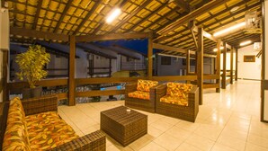 A covered outdoor seating area with wicker furniture and a potted plant. - Hotel Bem Brasil (Porto Seguro)