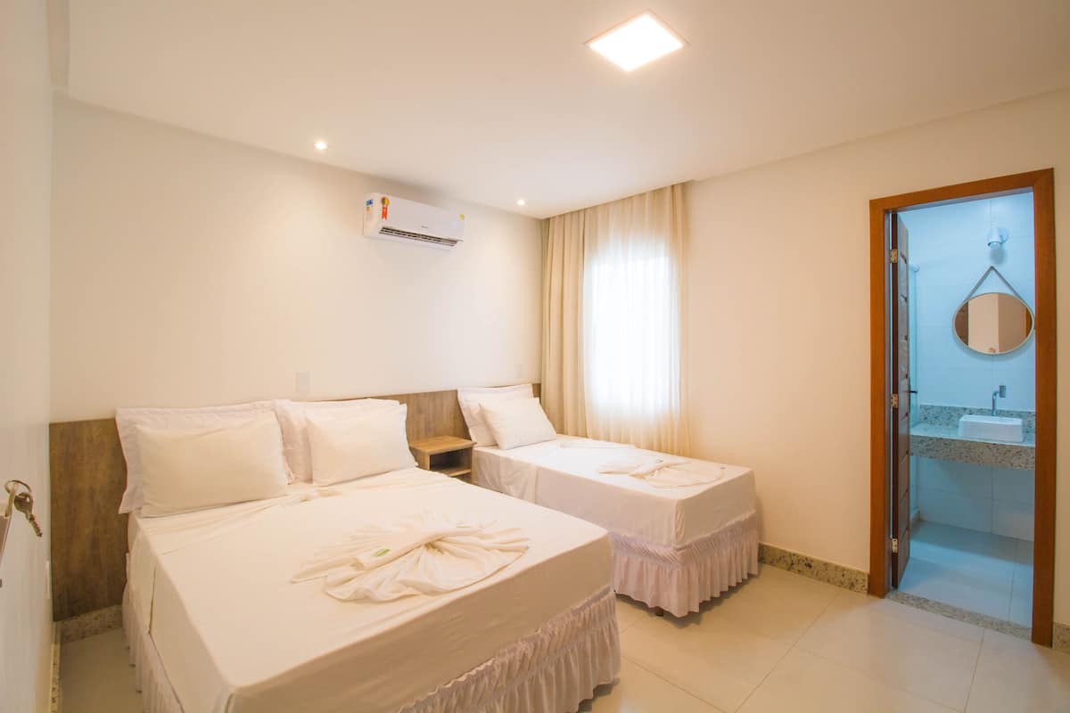 A hotel room with two beds, a bathroom with a sink, and a door leading to a balcony.