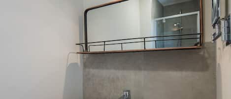 Un baño con lavamanos blanco, encimera de madera y un espejo encima.