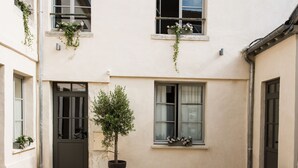 A building with a tiled courtyard, a central door, and windows with plants. - Hôtel Le Chantilly (Chantilly)