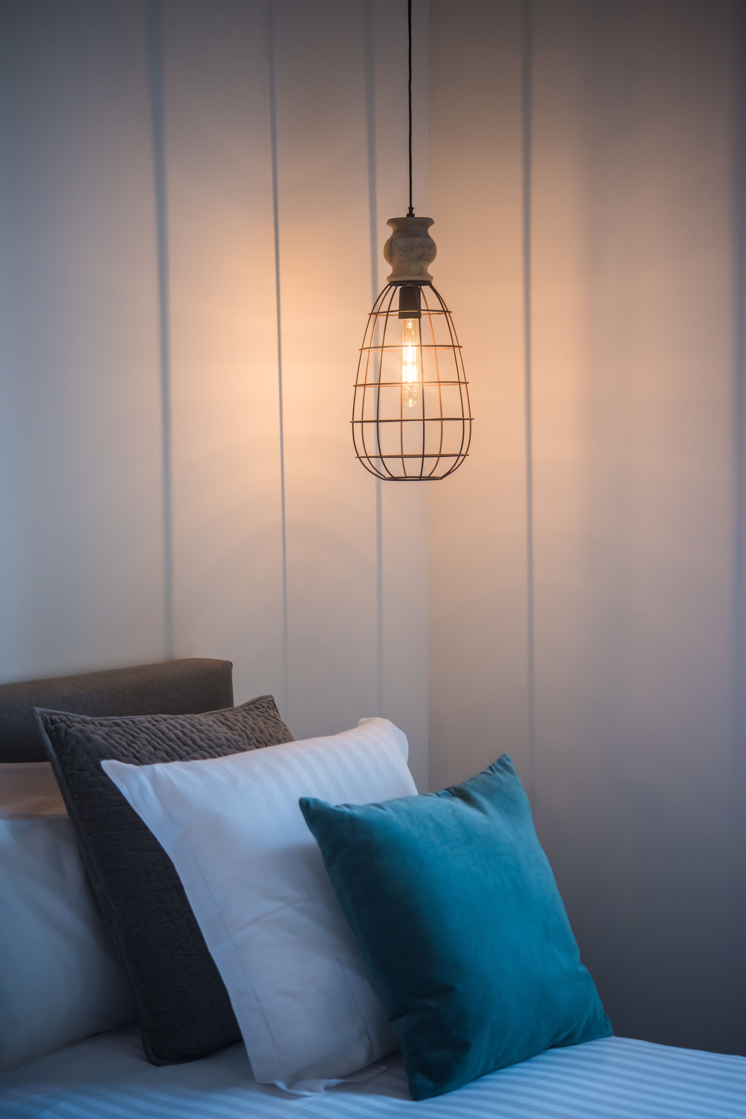 A bed with a headboard, pillows, and a hanging light fixture.