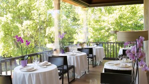 An outdoor dining area with round tables, chairs, and white tablecloths.