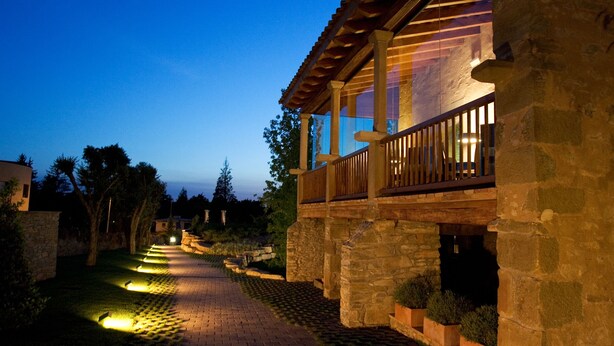 A stone building with a wooden balcony and a paved pathway.