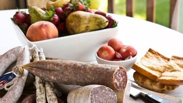 Una selección de embutidos curados y frutas frescas sobre una tabla de madera.