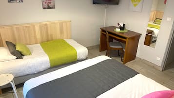 Habitación de hotel con dos camas, un escritorio, una silla, un televisor y obras de arte en las paredes.