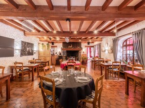A restaurant with wooden beams and hexagonal tile flooring. Tables are set with white tablecloths and chairs. -   AUBERGE CAMILLE ET SIMON (Saint-Agnan)