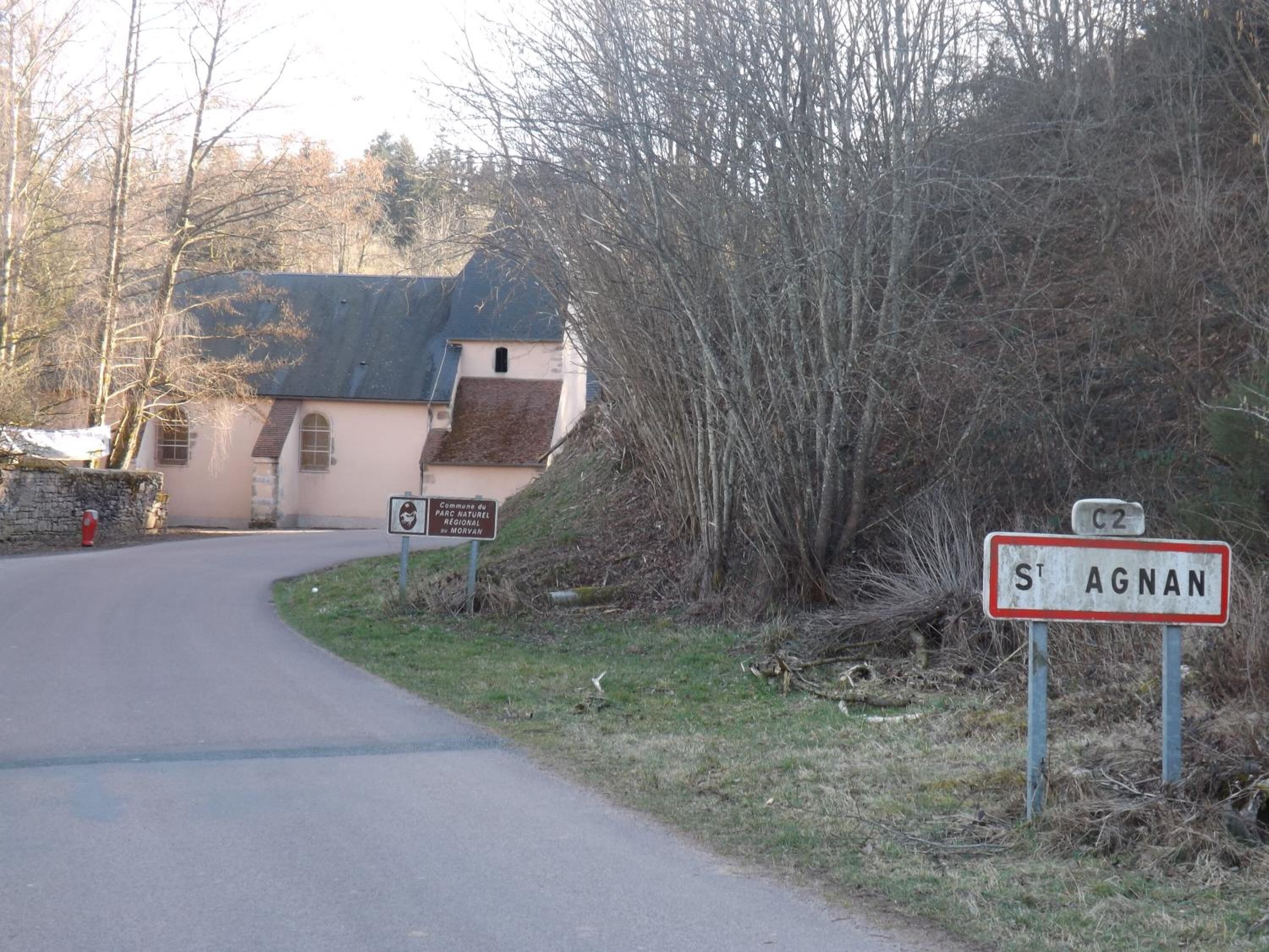 A rural road with a sign for St. Agnan and a sign for Parc Naturel Regional de Morvan.