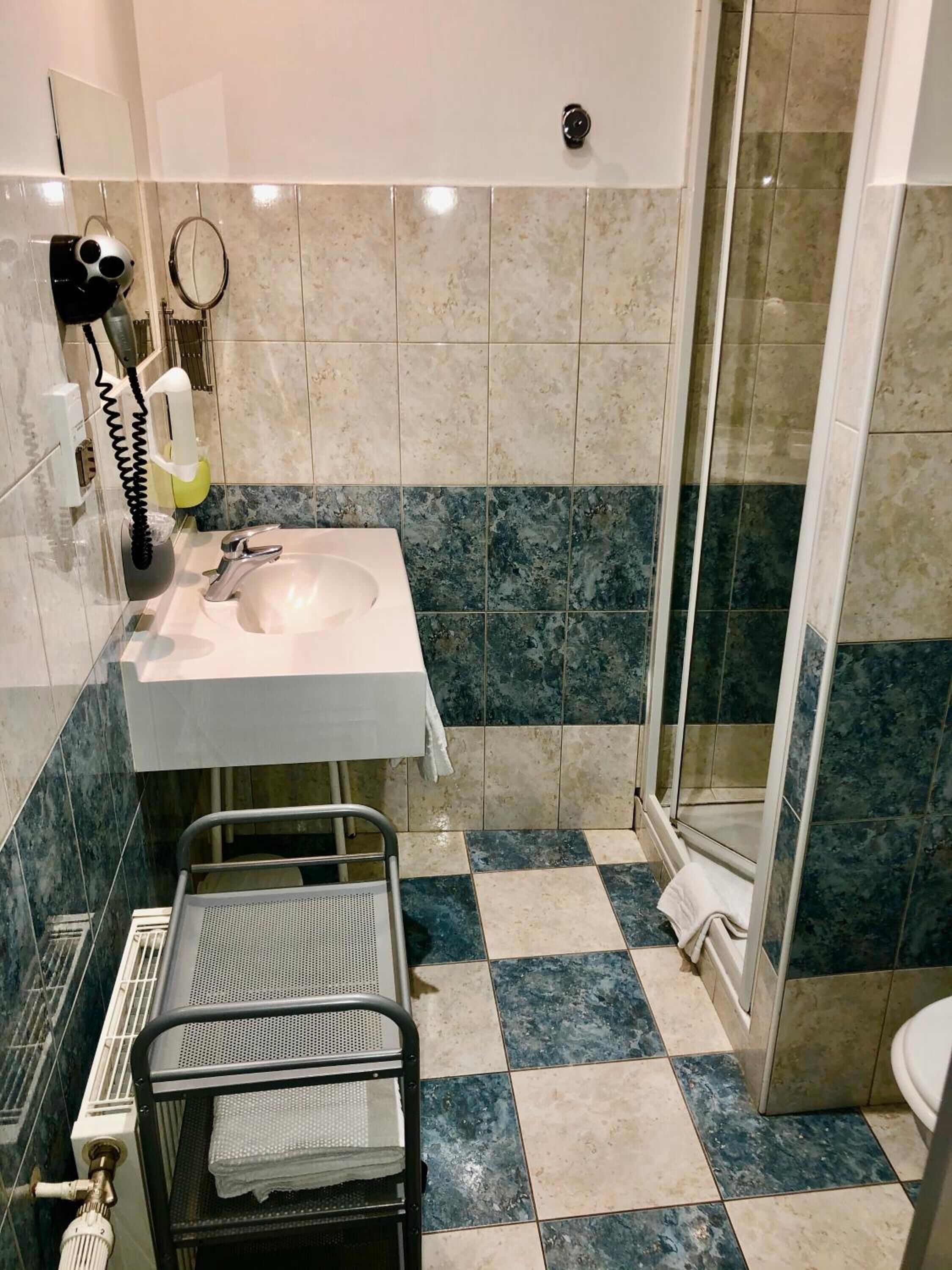 Un baño con lavamanos, espejo, secador de pelo y toallero.