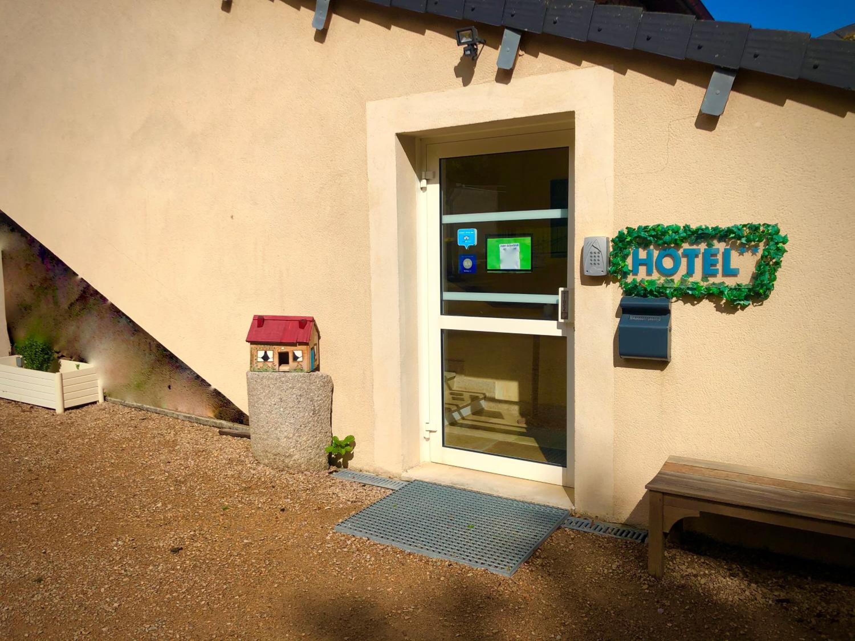 A hotel entrance with a glass door, a small house model, and a 'HOTEL' sign on the wall.