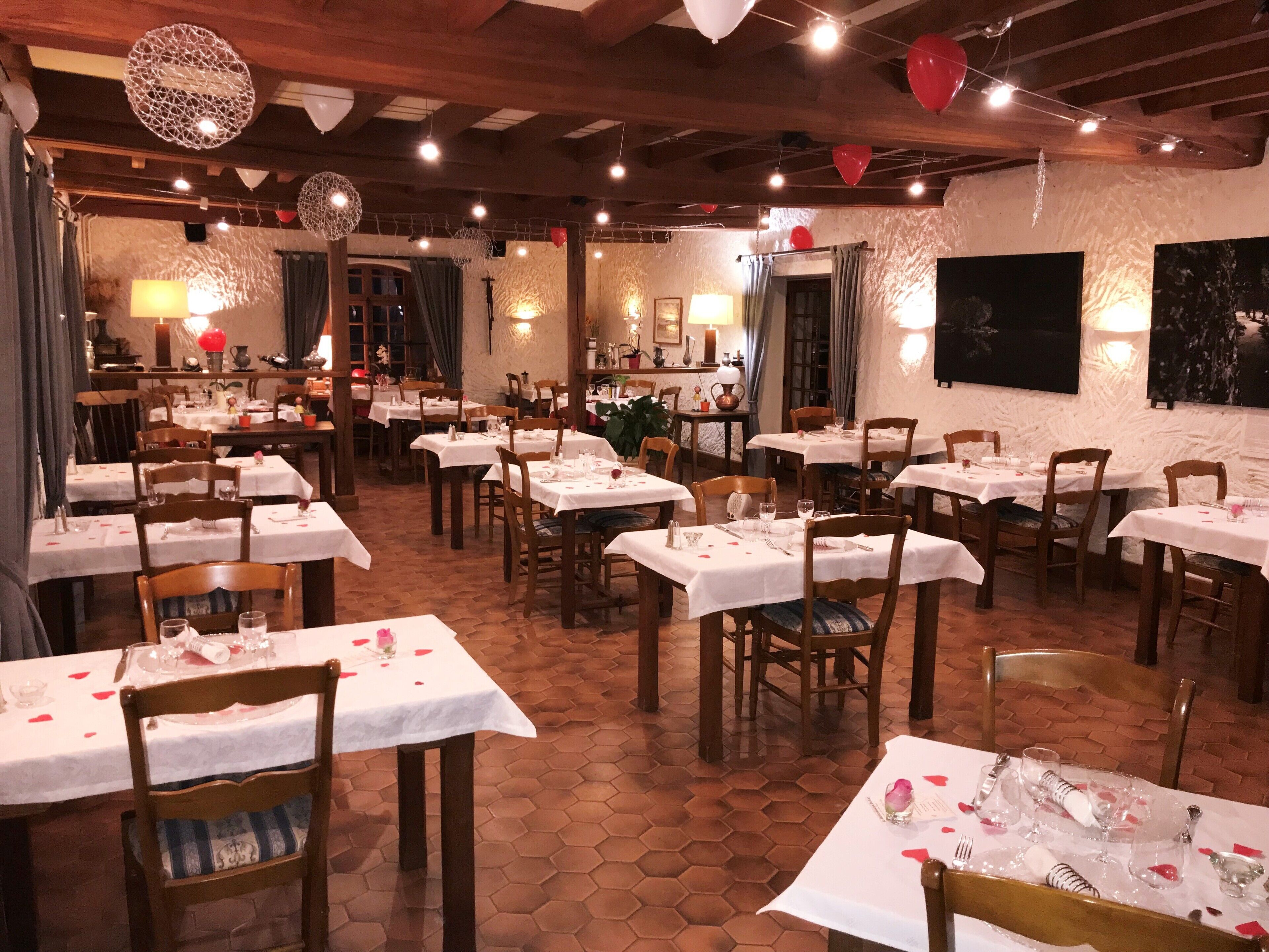 A restaurant with multiple tables set for dining, wooden chairs, and a hexagonal tiled floor.