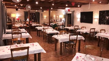 A restaurant with multiple tables set for dining, wooden chairs, and a hexagonal tiled floor.