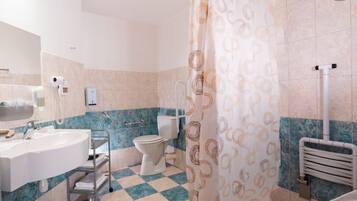 Une salle de bain comprenant un lavabo, des toilettes et un espace douche.
