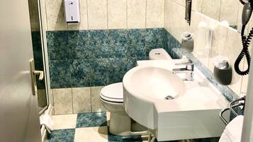 Un baño con inodoro, lavamanos y secamanos.