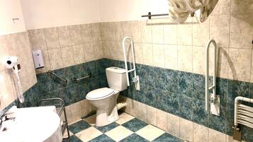A bathroom with a toilet, a sink, and a shower with grab bars.