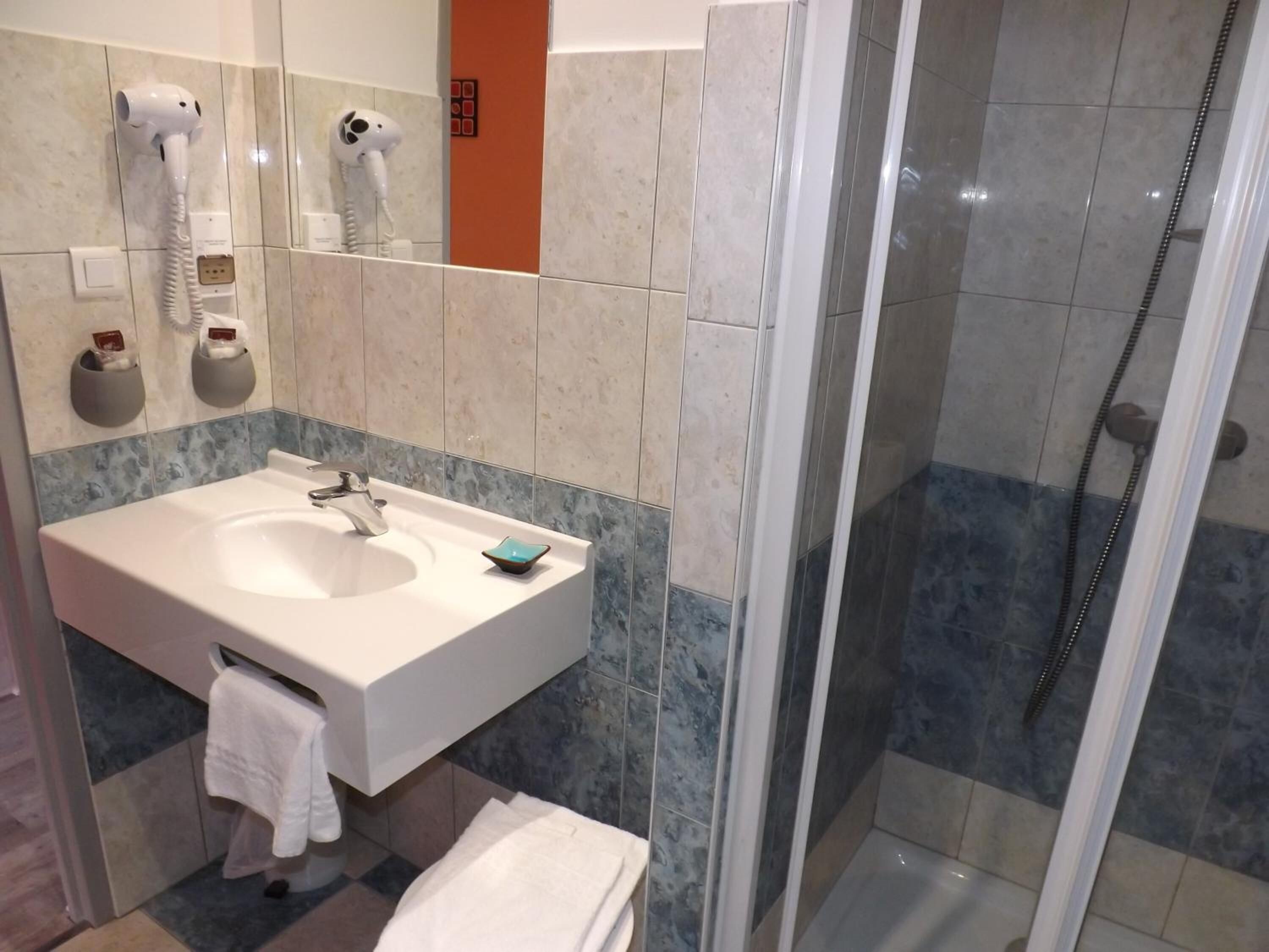 Un baño con lavamanos, toallero y zona de ducha.