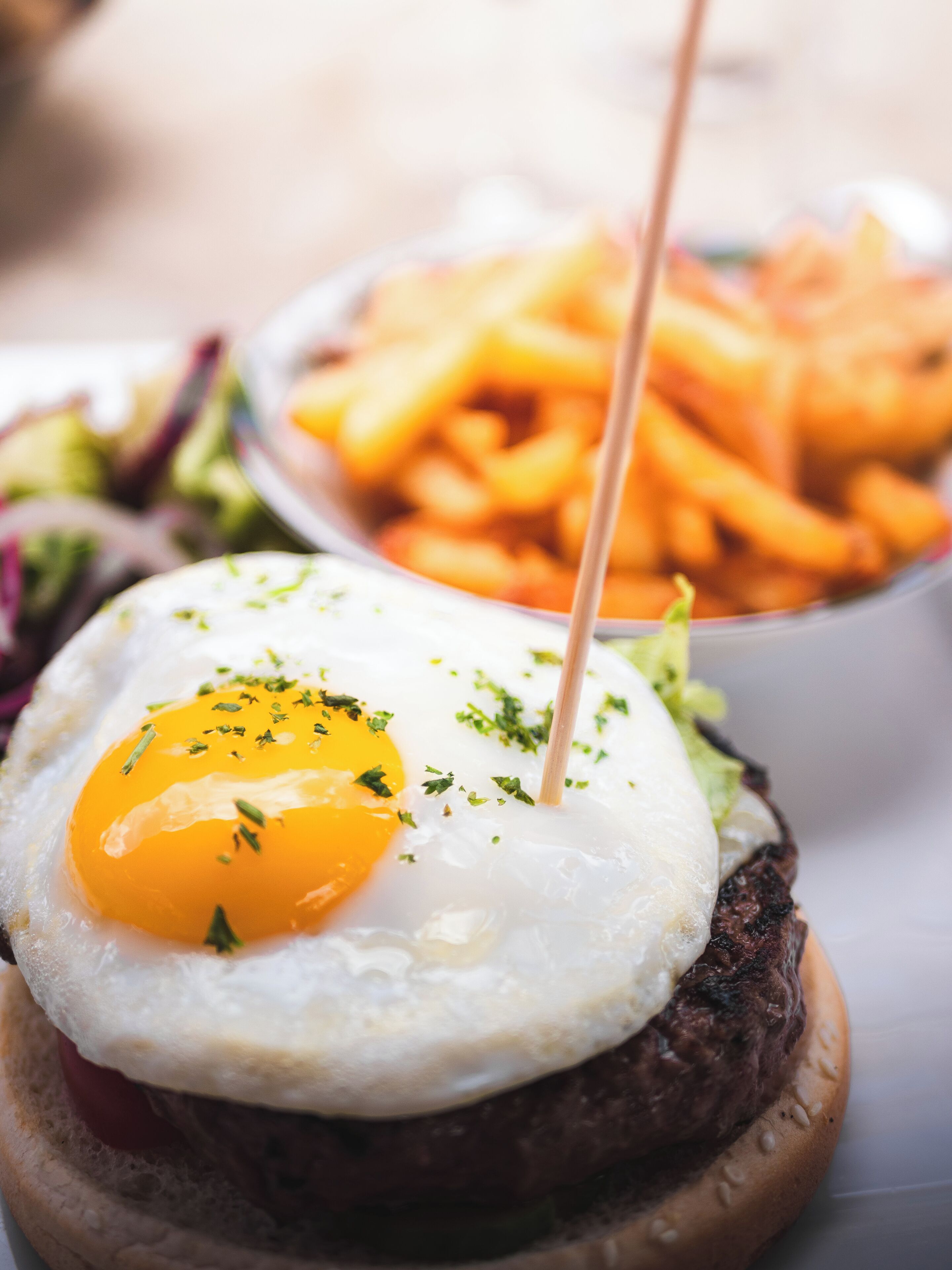 A burger with a fried egg and a side of fries.