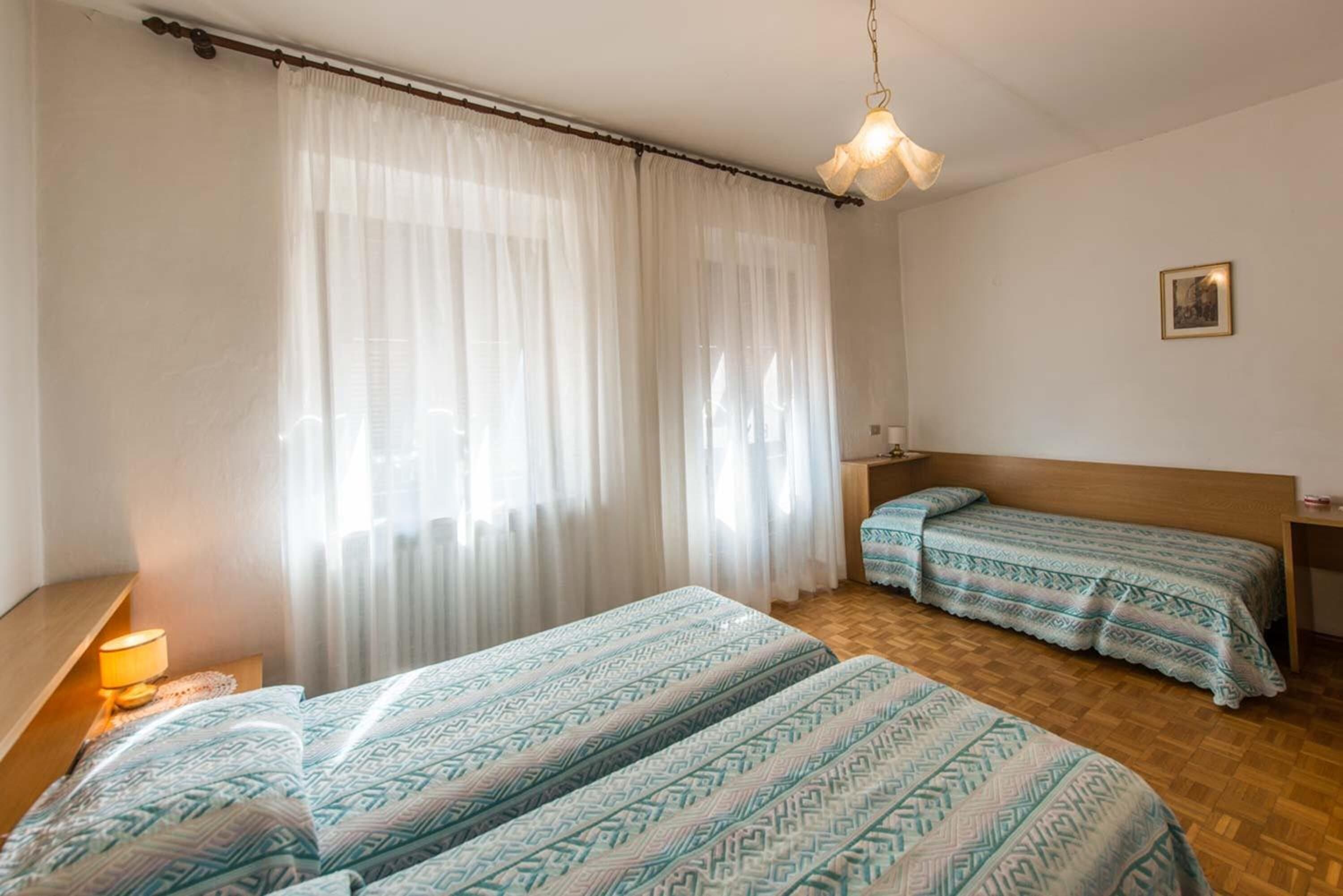 Una camera con due letti, un poggiatesta in legno, un comodino con una lampada e un lampadario.