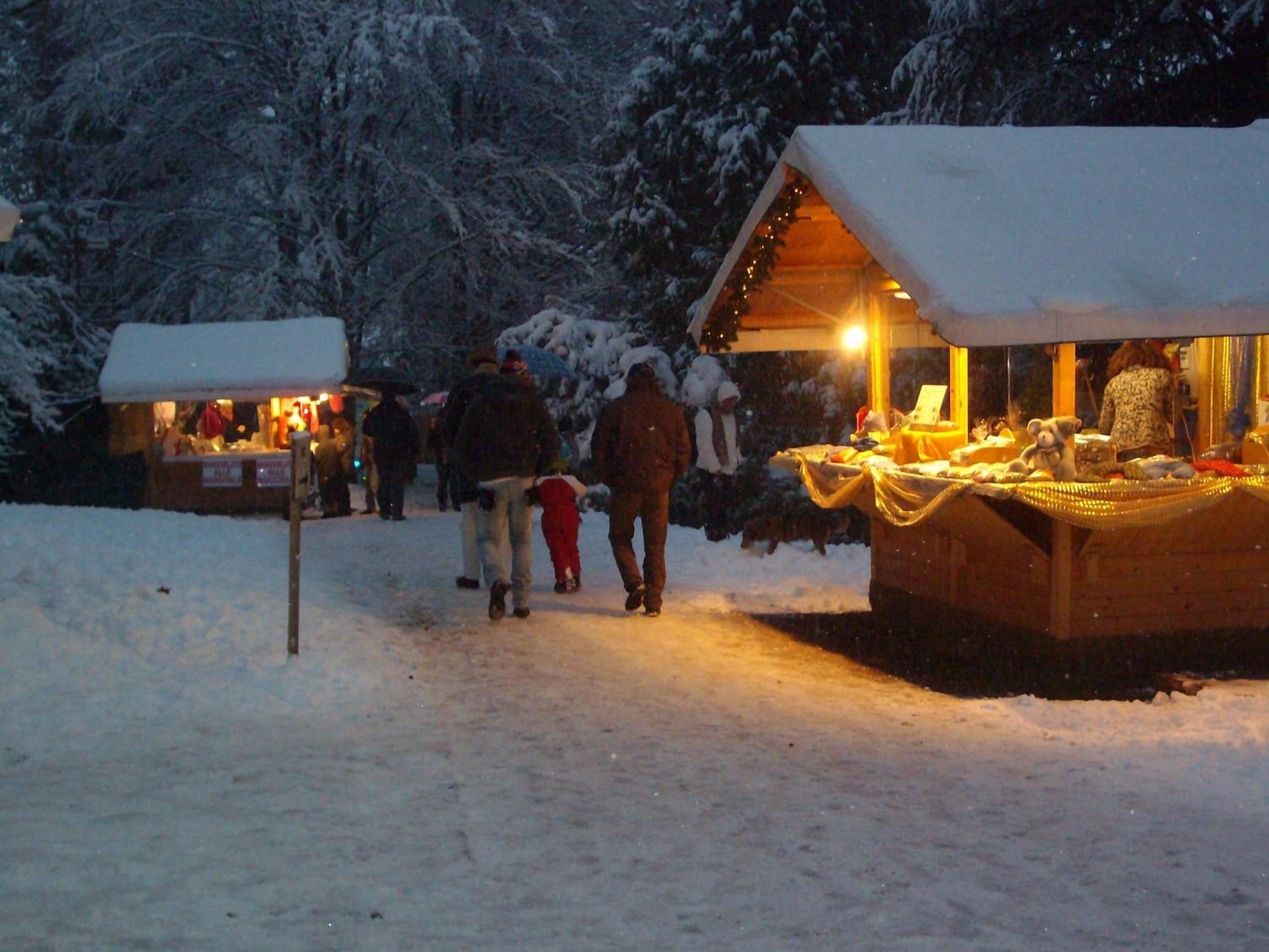 Un mercado al aire libre nevado con puestos y una zona cubierta.